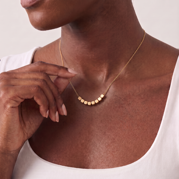 Block Necklace in gold, worn at the collarbone: eight small blocks on a fine chain