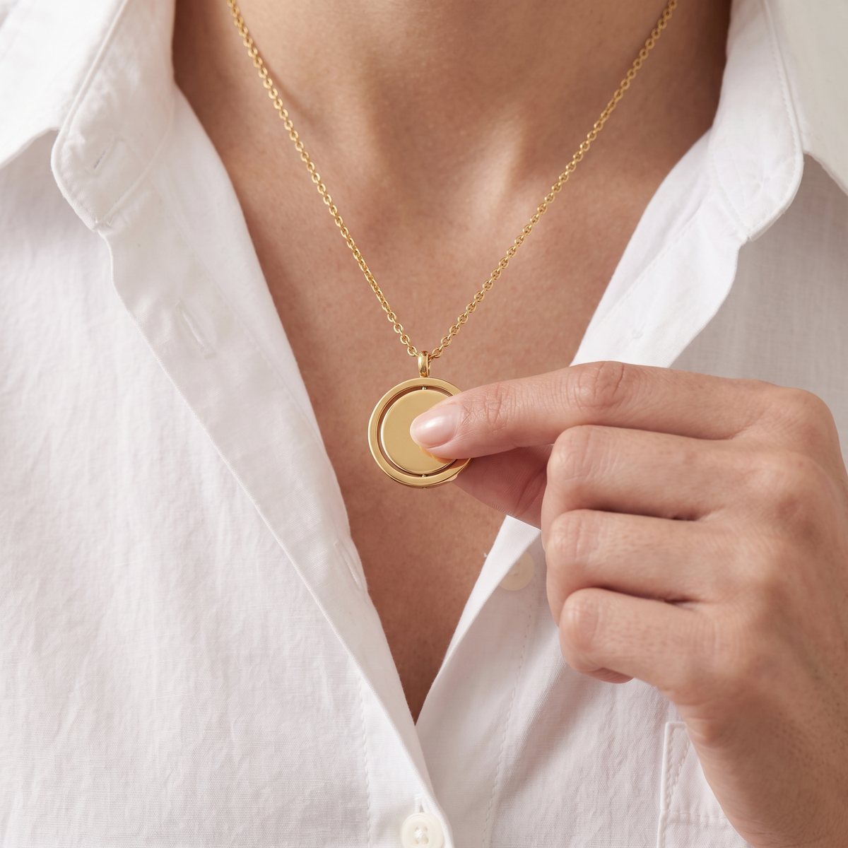 Spinner Necklace in gold, worn with the disc turning under a thumb