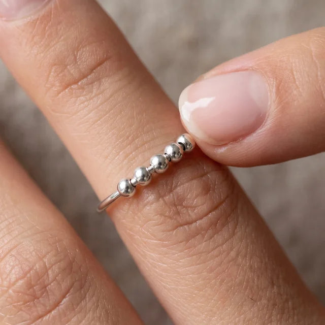 Slider Ring in silver, worn on the hand, a fingertip moving the beads