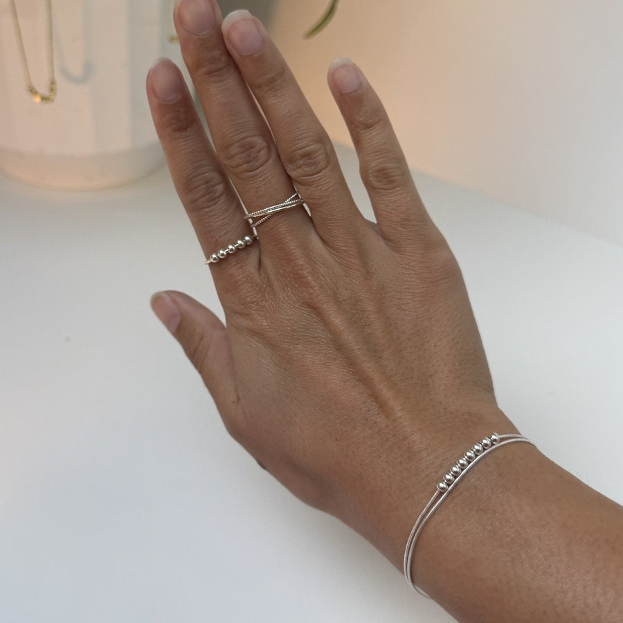 A hand wearing the Slider Ring and Rope Ring in silver with the Snake Bracelet at the wrist